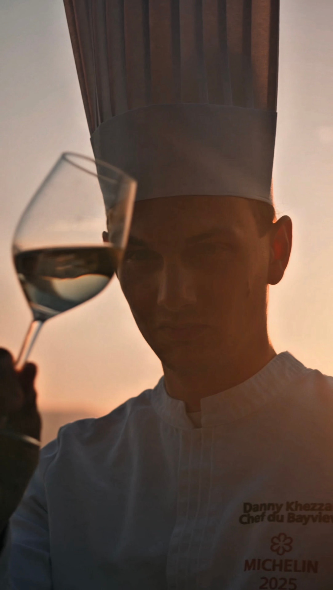 Danny Khezzar levant un verre de la cuvée blanche au coucher du soleil